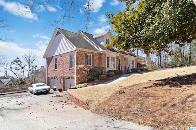 view of property exterior featuring an attached garage, brick siding, and driveway