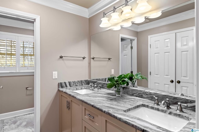 bathroom with crown molding, double vanity, baseboards, and a sink