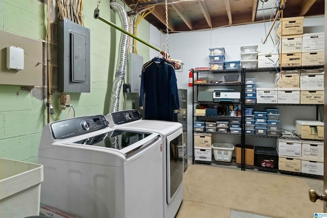 laundry room featuring concrete block wall, laundry area, electric panel, a sink, and washer and dryer