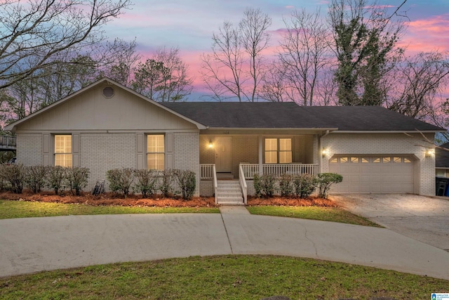 ranch-style home featuring a garage, covered porch, brick siding, and driveway