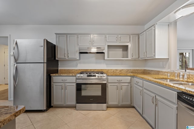 kitchen with light tile patterned floors, light stone counters, under cabinet range hood, a sink, and appliances with stainless steel finishes