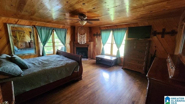 bedroom featuring multiple windows, wooden ceiling, wood finished floors, and wooden walls