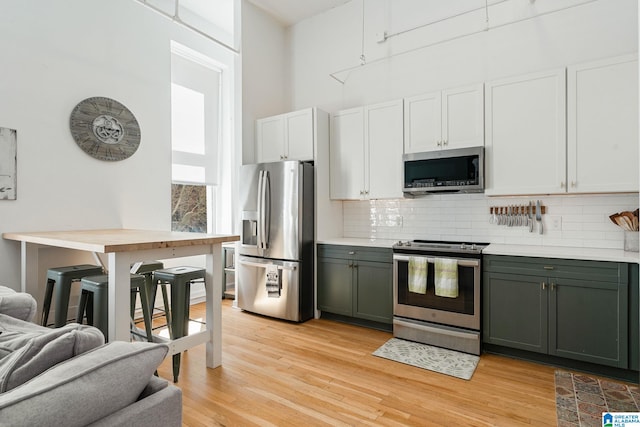 300 20th Ave N Unit 204, Birmingham, AL 35203 - kitchen with light wood finished floors, stainless steel appliances, a high ceiling, light countertops, and decorative backsplash