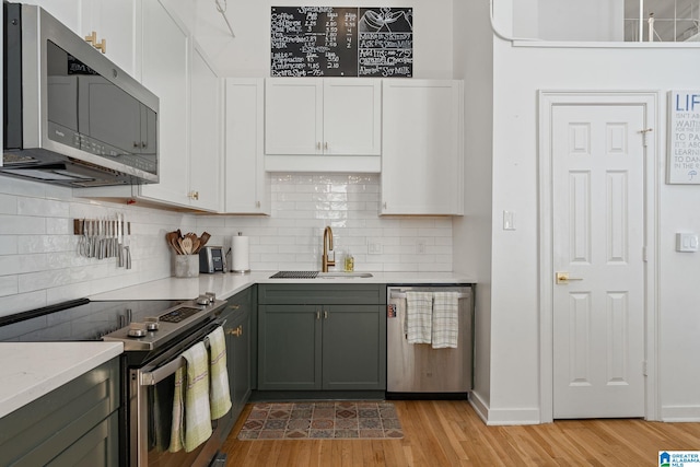 300 20th Ave N Unit 204, Birmingham, AL 35203 - kitchen featuring light wood finished floors, a sink, appliances with stainless steel finishes, white cabinetry, and backsplash