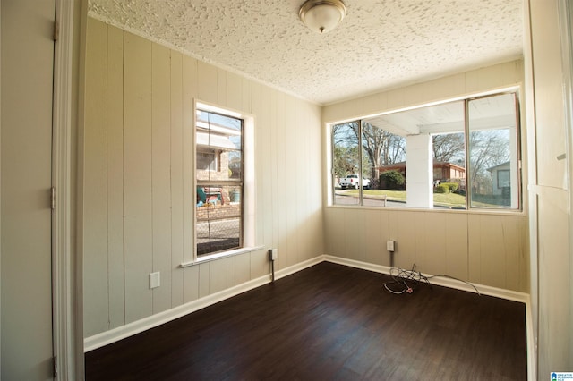 unfurnished room featuring a textured ceiling, dark wood-style flooring, and baseboards