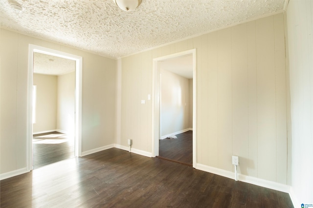 spare room featuring baseboards, dark wood finished floors, and a textured ceiling