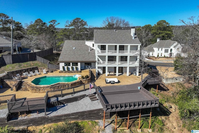 back of property with a balcony, a fenced backyard, an outdoor pool, and a patio