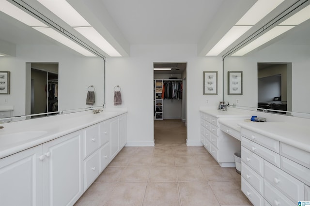 bathroom featuring tile patterned flooring, a walk in closet, a sink, and double vanity