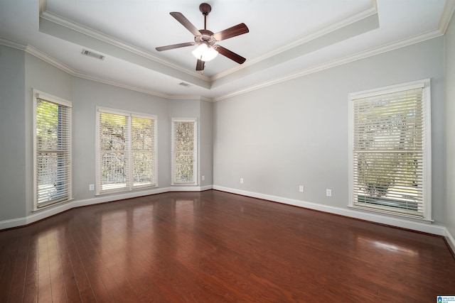 empty room with wood-type flooring, visible vents, a raised ceiling, and a wealth of natural light