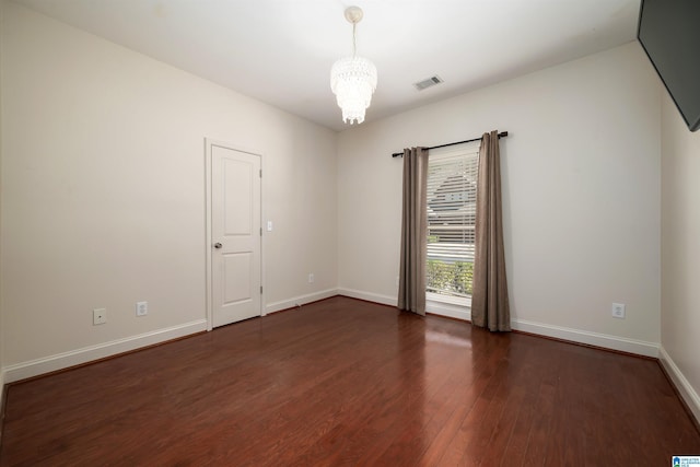 unfurnished room featuring a notable chandelier, dark wood-style flooring, visible vents, and baseboards