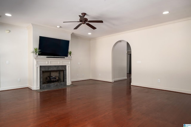 unfurnished living room featuring arched walkways, dark wood finished floors, and baseboards