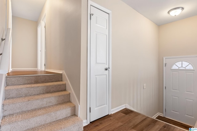 entryway with stairs, baseboards, and dark wood-type flooring