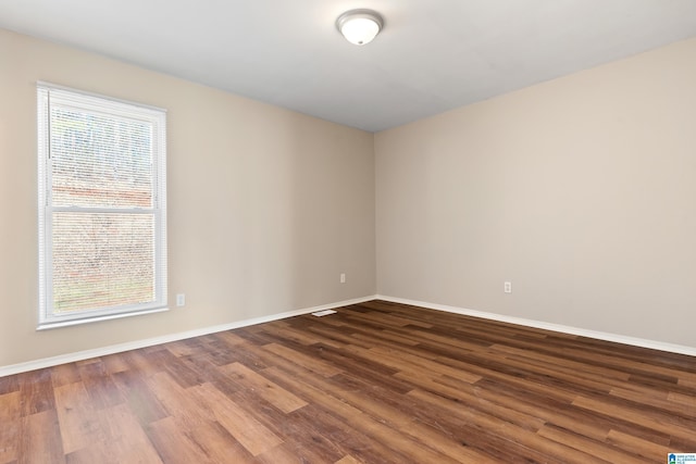 unfurnished room with dark wood-style floors and baseboards