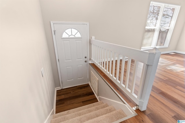 staircase with a wealth of natural light, baseboards, and wood finished floors