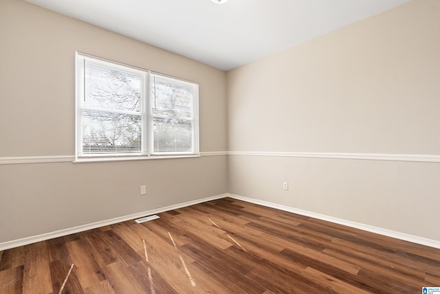 unfurnished room featuring baseboards, visible vents, and wood finished floors