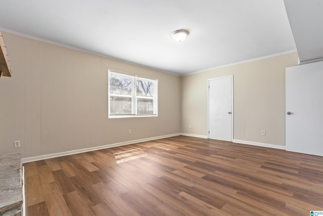 empty room with baseboards, ornamental molding, and wood finished floors