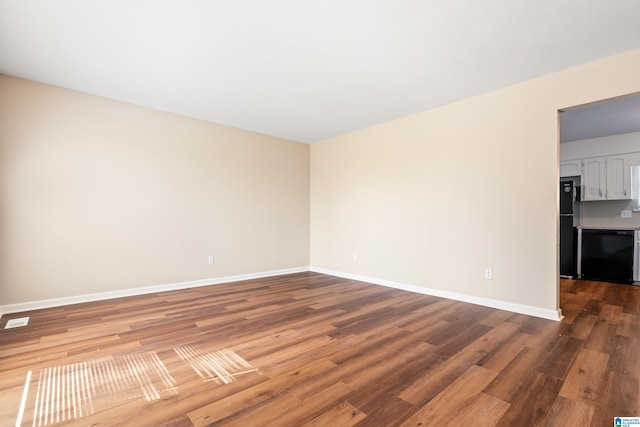 empty room with wood finished floors, visible vents, and baseboards