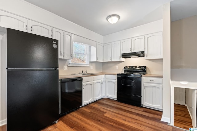 kitchen with dark wood-type flooring, under cabinet range hood, light countertops, black appliances, and white cabinetry