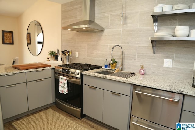 kitchen featuring open shelves, wall chimney exhaust hood, gray cabinets, and appliances with stainless steel finishes