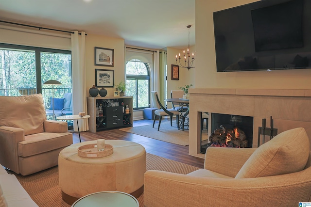 living area featuring a glass covered fireplace, a chandelier, and wood finished floors