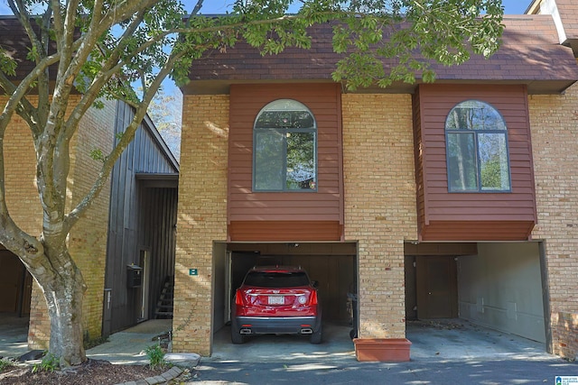 view of front of house with an attached garage, brick siding, and driveway