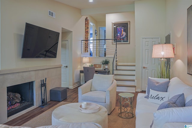 living area featuring visible vents, wood finished floors, a high end fireplace, baseboards, and stairs