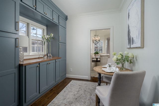 interior space with dark wood-style floors, baseboards, wooden counters, ornamental molding, and a chandelier