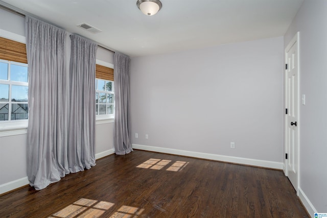 unfurnished room with wood finished floors, visible vents, and baseboards