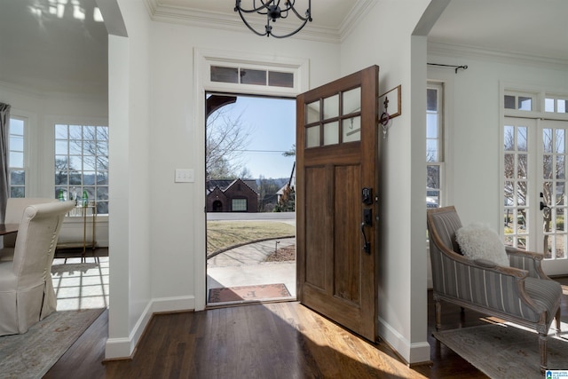 entryway featuring crown molding, baseboards, a chandelier, wood finished floors, and arched walkways