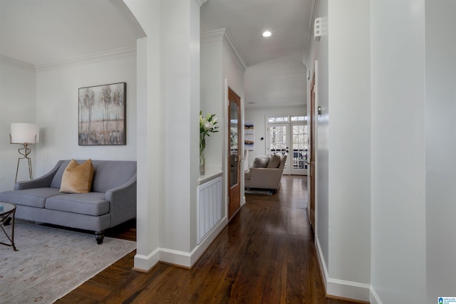 corridor featuring crown molding, baseboards, arched walkways, and dark wood-style flooring