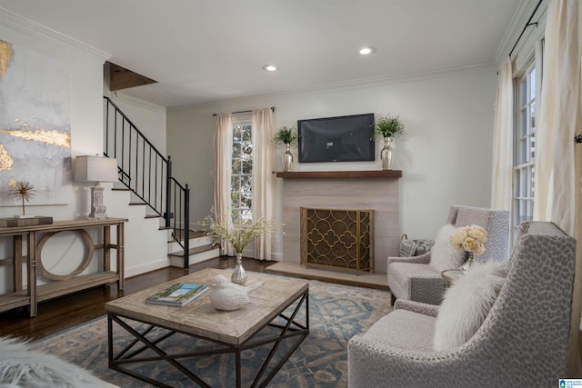 living area featuring a fireplace with raised hearth, crown molding, stairs, recessed lighting, and wood finished floors