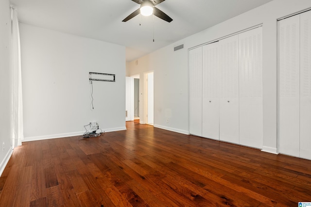 unfurnished bedroom with wood finished floors, visible vents, two closets, and baseboards