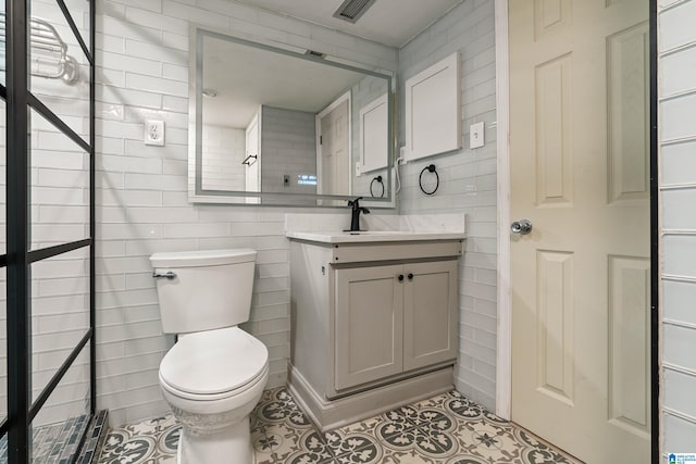 bathroom featuring tile patterned flooring, tile walls, toilet, and vanity