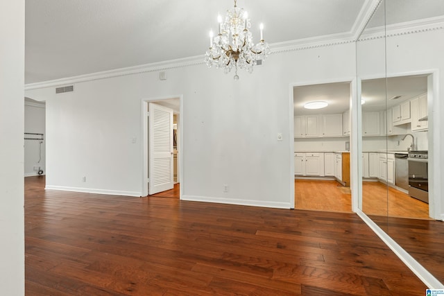 unfurnished living room with visible vents, ornamental molding, hardwood / wood-style floors, an inviting chandelier, and baseboards