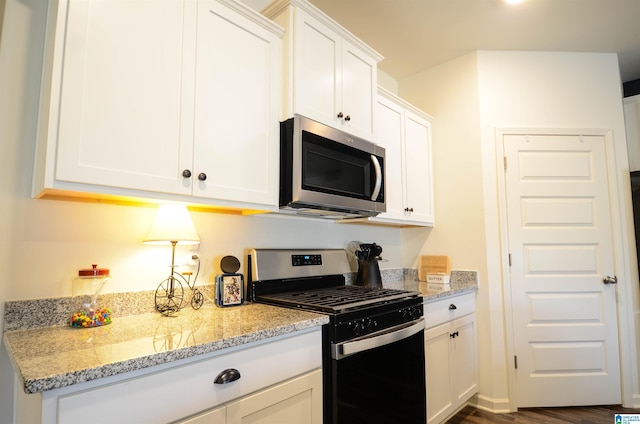 kitchen featuring appliances with stainless steel finishes, dark wood-style flooring, white cabinets, and light stone counters