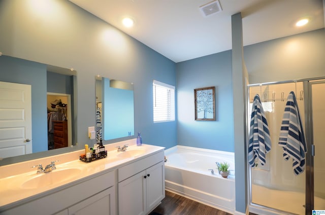 bathroom with visible vents, a sink, a shower stall, and a garden tub