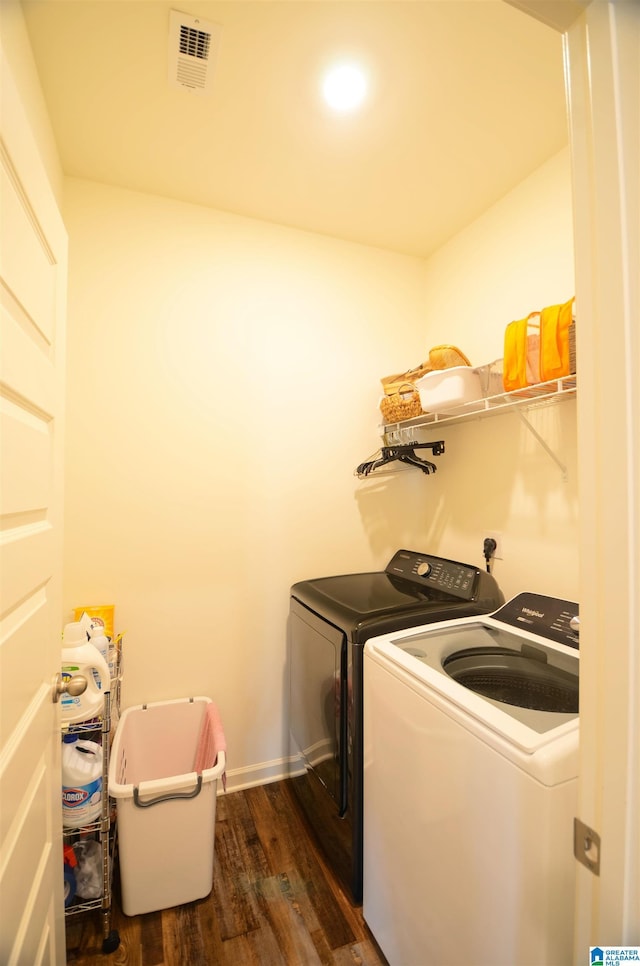 clothes washing area featuring laundry area, dark wood-type flooring, visible vents, and washer and dryer