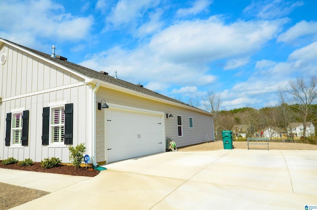 view of side of home featuring driveway, board and batten siding, and roof with shingles