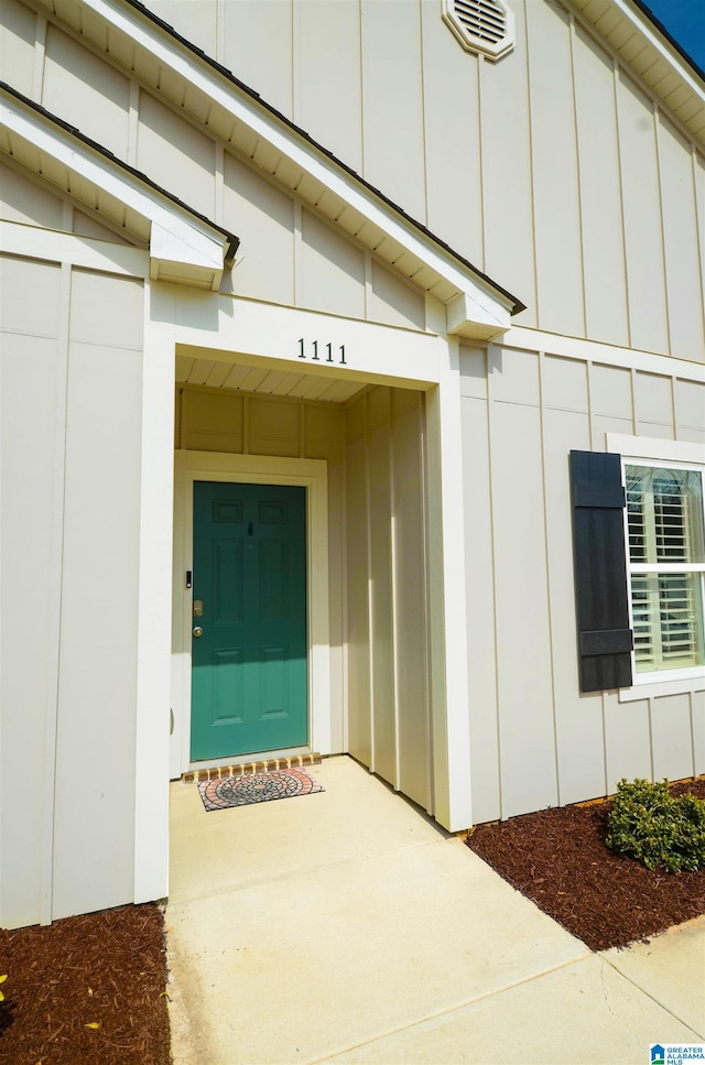 doorway to property featuring board and batten siding and visible vents