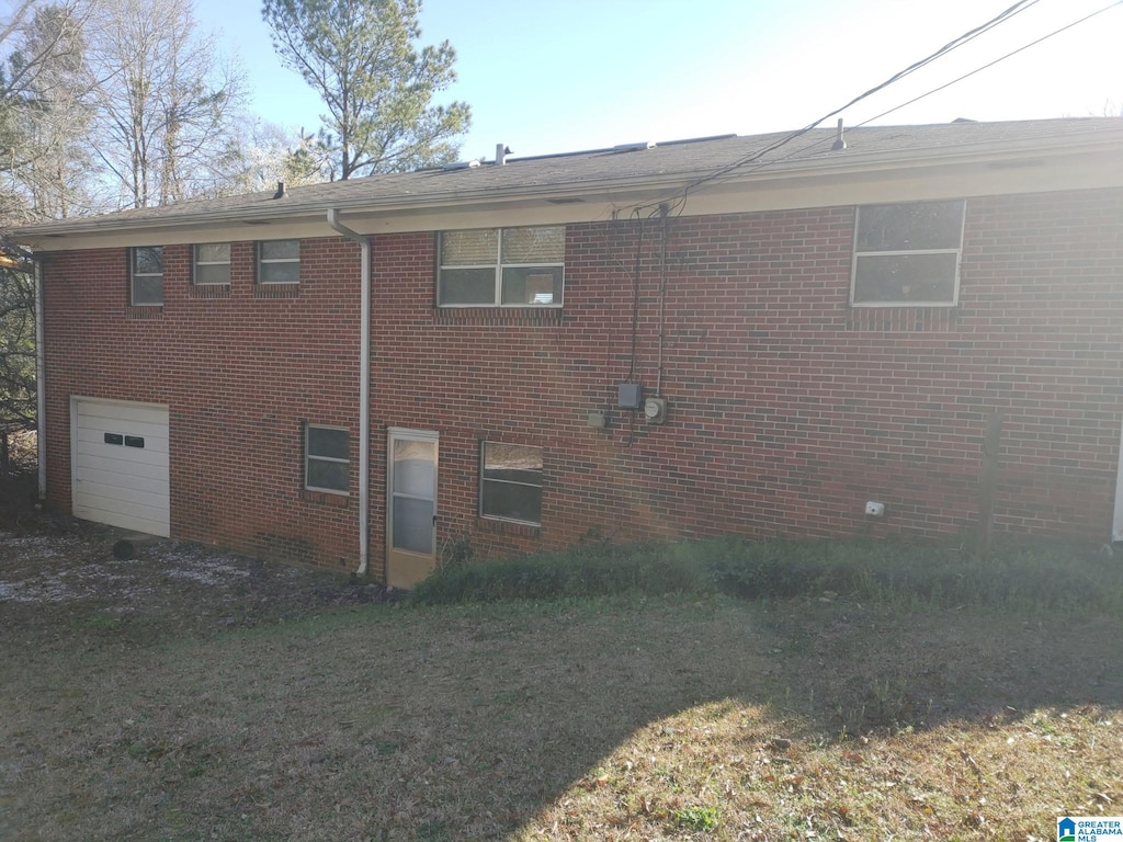 view of side of home featuring a garage, a yard, and brick siding