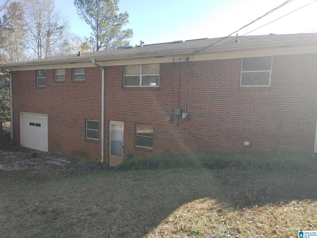 view of side of home featuring a garage, a yard, and brick siding