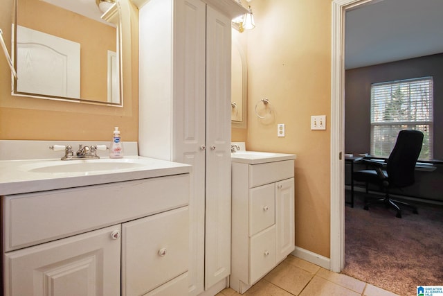 bathroom featuring a sink, baseboards, two vanities, and tile patterned floors