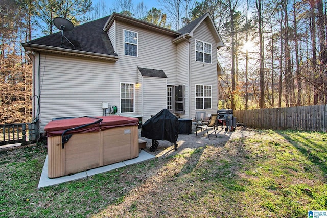 back of house with a hot tub, fence, roof with shingles, a yard, and a patio area