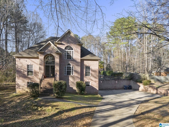 view of front facade featuring fence, brick siding, and driveway