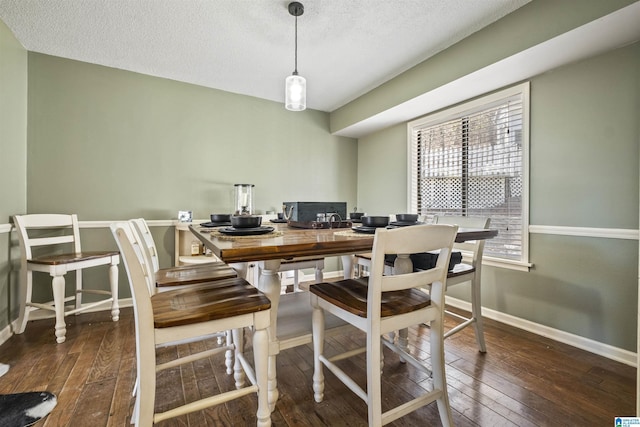 dining room featuring a textured ceiling, baseboards, and hardwood / wood-style floors