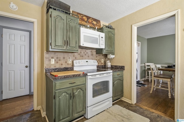 kitchen with dark countertops, white appliances, green cabinetry, and backsplash