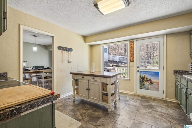 kitchen with a textured ceiling, a textured wall, and baseboards