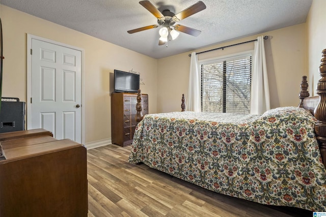 bedroom featuring ceiling fan, a textured ceiling, baseboards, and wood finished floors