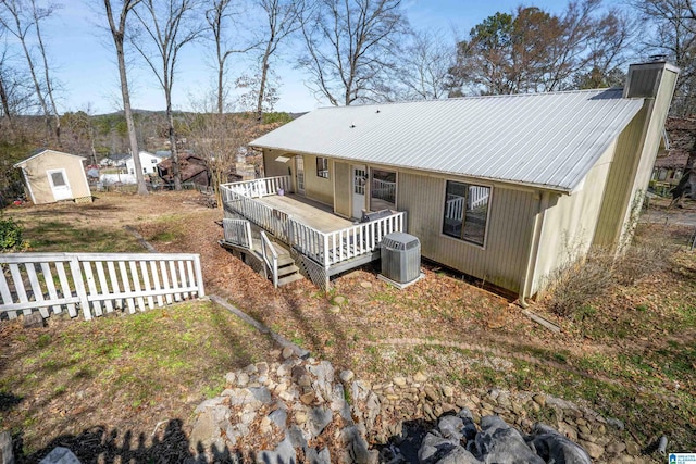 rear view of property featuring a deck, metal roof, cooling unit, and an outdoor structure