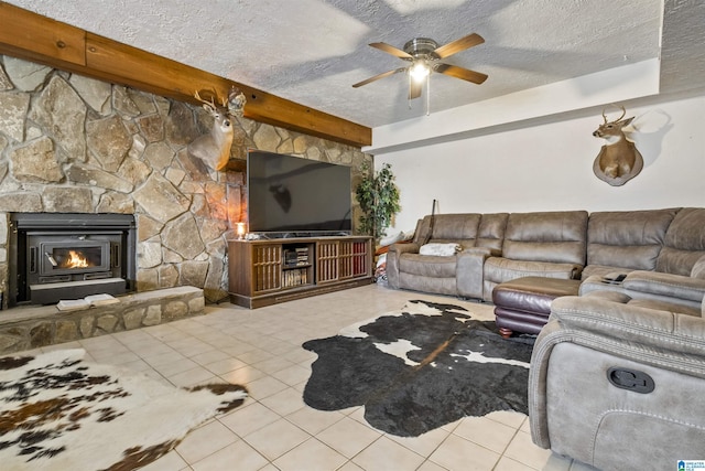 living area with a stone fireplace, beamed ceiling, a textured ceiling, and tile patterned floors